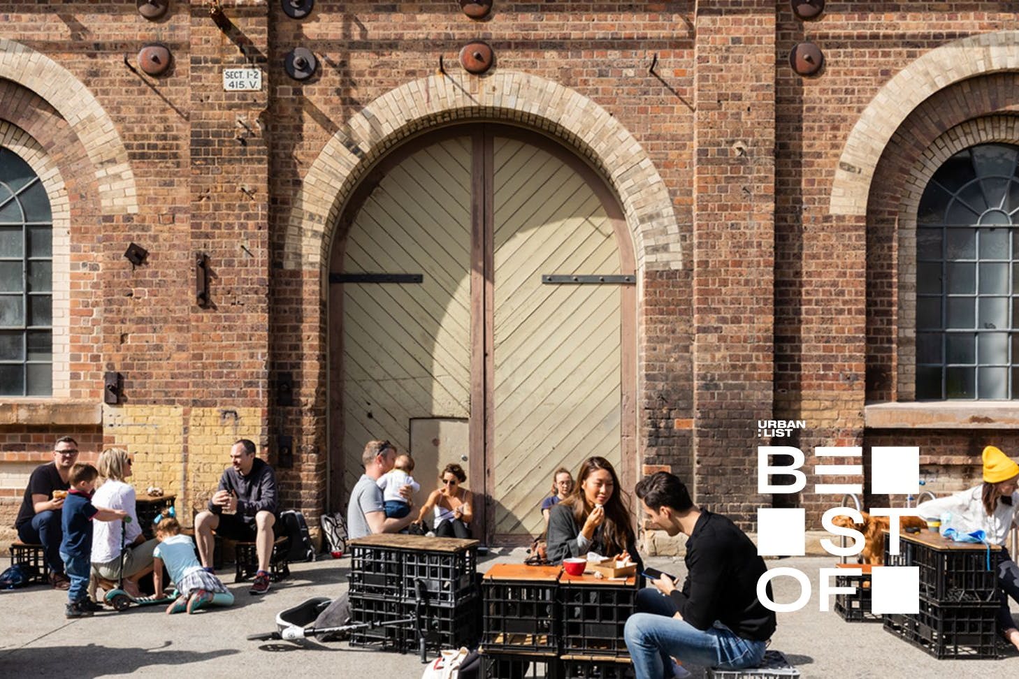 people sitting on milk crates and eating street food at markets in sydney on a sunny day